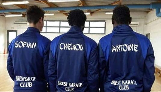 Trois compétiteurs de dos portant la veste bleue du Brest Karaté Club floquée à leur prénom