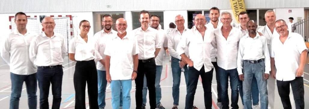 Groupe de juges et d’officiels réunis dans un gymnase à l’issue d’une compétition de karaté