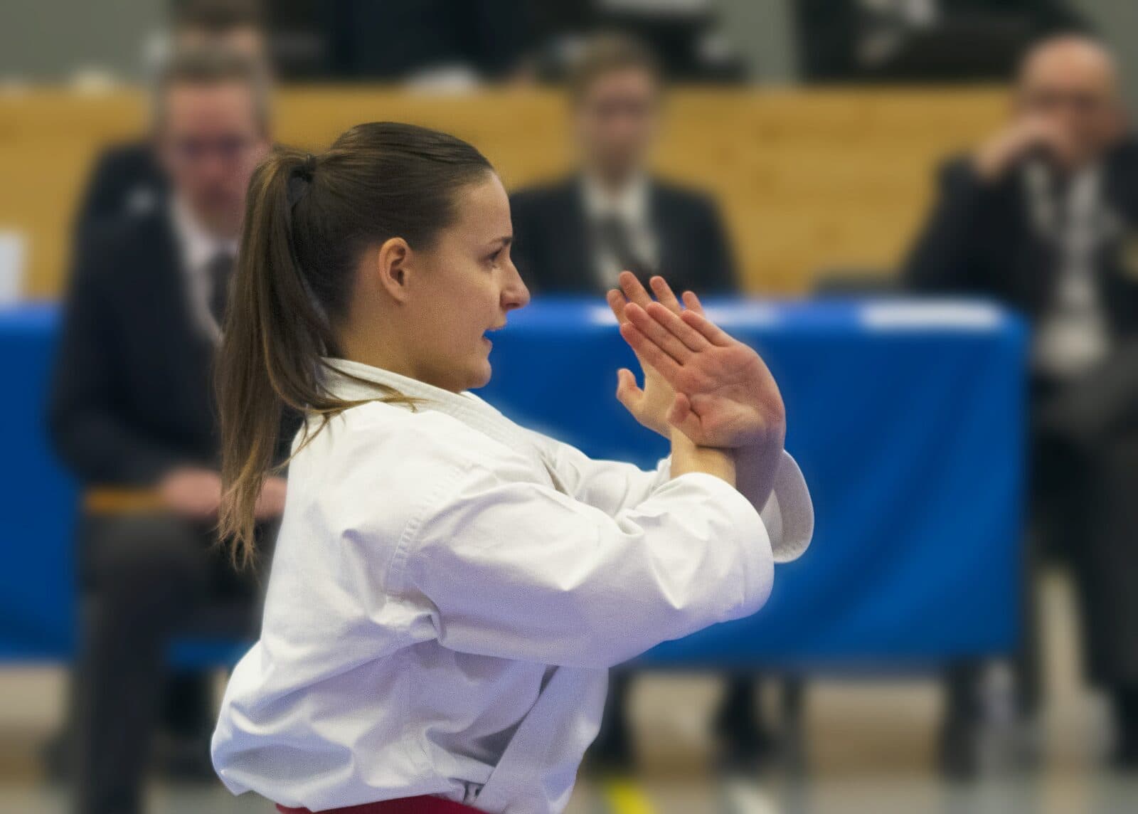 Karatéka ceinture rouge exécutant une technique de mains de profil devant le jury